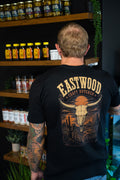 Back of black Eastwood Craft Butcher T-shirt featuring a longhorn skull, cacti, and orange desert sunset